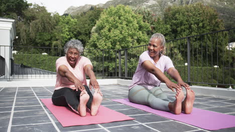 Glückliche-ältere-Afroamerikanische-Freundinnen,-Die-Yoga-Praktizieren,-Sitzend-Auf-Dem-Balkon,-Zeitlupe