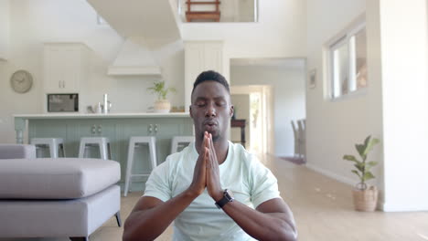 Hombre-Afroamericano-Enfocado-Practicando-Meditación-De-Yoga-En-Una-Sala-De-Estar-Soleada,-Cámara-Lenta