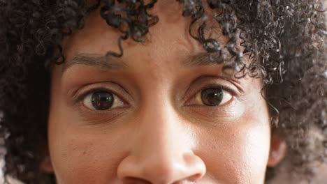 Retrato-De-Cerca-De-Ojos-Marrones-De-Una-Feliz-Mujer-Afroamericana-Sonriendo-Al-Sol,-Cámara-Lenta