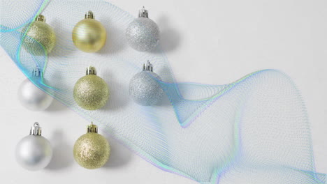 Animation-of-trails-of-blue-light-over-christmas-baubles-decorations