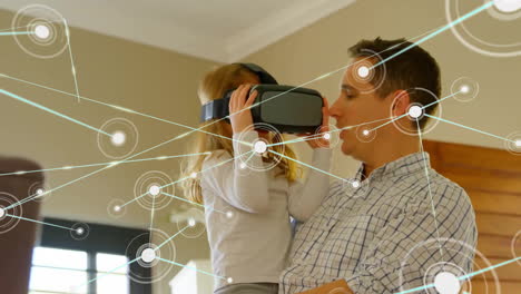 Animation-of-communication-network-over-caucasian-father-holding-daughter-wearing-vr-headset