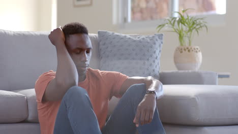 Hombre-Afroamericano-Preocupado-Sentado-Y-Pensando-En-Una-Sala-De-Estar-Soleada,-Cámara-Lenta