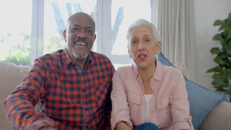 Portrait-of-happy-senior-biracial-couple-sitting-on-couch-having-video-call-at-home,-slow-motion