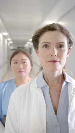 Vertical-video-portrait-of-diverse-female-doctors-in-hospital-corridor,-slow-motion