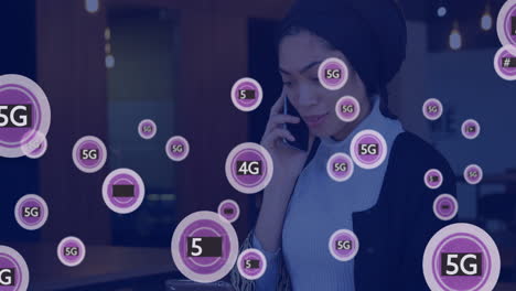 Animation-Von-5G-Symbolen-über-Einer-Gemischtrassigen-Geschäftsfrau,-Die-Ein-Tablet-Verwendet-Und-Auf-Dem-Smartphone-Spricht