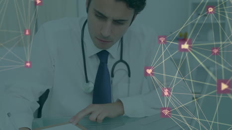 Animation-of-network-of-connections-with-icons-over-caucasian-male-doctor-taking-notes