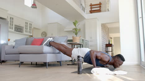 Focused-african-american-man-doing-push-ups-on-couch-in-sunny-living-room,-slow-motion