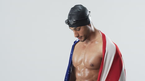 Young-biracial-athlete-swimmer-draped-in-an-American-flag-at-a-photo-studio
