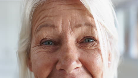 Eyes-of-happy-caucasian-senior-woman-standing-and-laughing-in-sunny-room-at-home,-slow-motion