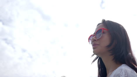 Happy-biracial-teenage-girl-in-sunglasses-smiling-against-sunny-cloudy-sky,-copy-space,-slow-motion