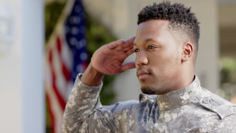 Glücklicher-Afroamerikanischer-Soldat,-Der-Zu-Hause-über-Der-Flagge-Der-USA-Salutiert,-Zeitlupe