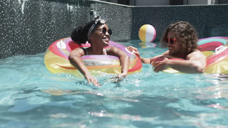 Diverse-couple,-a-young-African-American-woman-and-Caucasian-man,-enjoy-pool-time