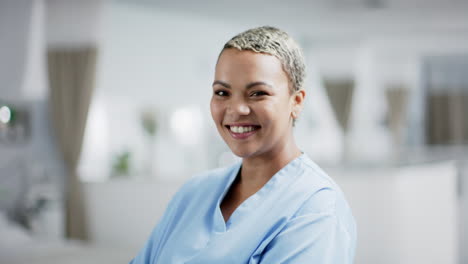 Portrait-of-happy-biracial-female-doctor-wearing-scrubs-in-hospital,-slow-motion