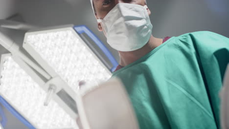 Caucasian-male-surgeon-using-defibrillator-in-operating-theatre-at-hospital,-slow-motion