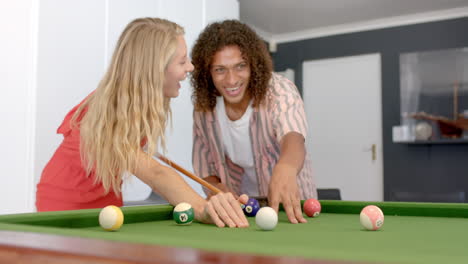 Young-Caucasian-woman-and-biracial-man-enjoy-a-game-of-pool-at-home
