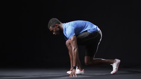 Afroamerikanischer-Athlet-In-Der-Startposition-Eines-Läufers-Auf-Schwarzem-Hintergrund