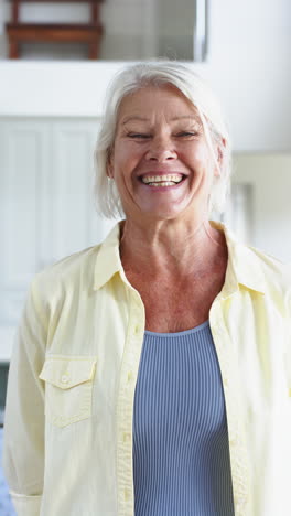 Happy-caucasian-senior-woman-standing-and-laughing-in-sunny-room,-slow-motion
