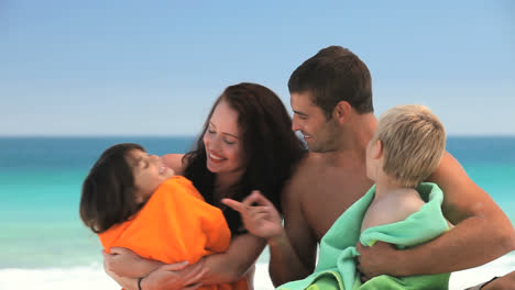 Eltern-Umarmen-Ihre-Kinder-Mit-Strandtüchern