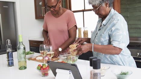 Focused-senior-african-american-female-friends-cooking-and-using-tablet,-copy-space,-slow-motion