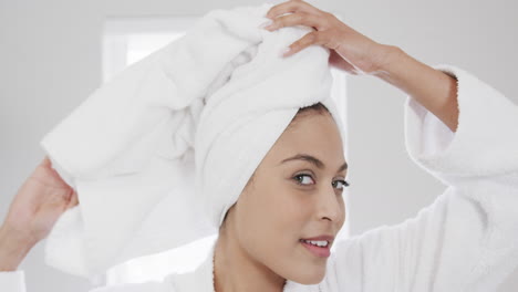 Portrait-of-happy-biracial-woman-wearing-towel-on-head-in-bathroom,-slow-motion