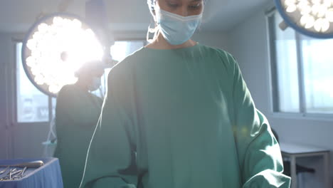 Porträt-Einer-Biracialen-Chirurgin-Beim-Sortieren-Chirurgischer-Instrumente-Im-Operationssaal,-Kopierraum,-Zeitlupe