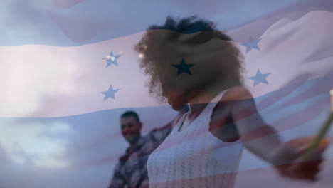 Animation-Der-Flagge-Von-Honduras-über-Einem-Glücklichen,-Vielfältigen-Paar,-Das-In-Der-Abenddämmerung-Mit-Wunderkerzen-Am-Strand-Tanzt