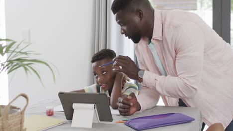 Un-Padre-Afroamericano-Ayuda-A-Su-Hijo-Con-La-Tarea-En-Casa-Usando-Una-Tableta