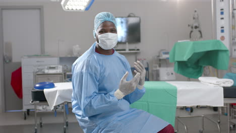 Portrait-of-african-american-male-surgeon-wearing-surgical-gown-in-operating-theatre,-slow-motion