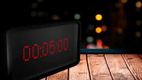 Animation-of-digital-clock-counting-down-to-midnight-with-lights-on-black-background