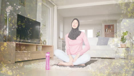 Animation-Von-Blättern-über-Einer-Gemischtrassigen-Frau-Im-Hijab,-Die-Yoga-Praktiziert