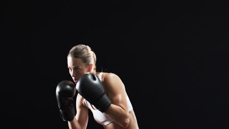 Young-Caucasian-woman-boxer-in-boxing-stance,-ready-to-train-on-black-background