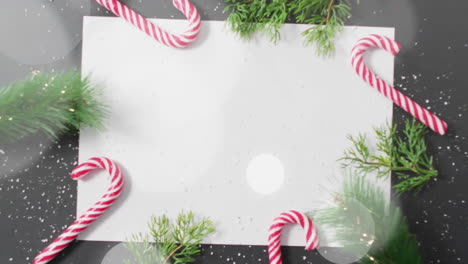 Animation-of-white-circles-over-christmas-tree-branches,-lollipops-and-blank-sheet-of-paper