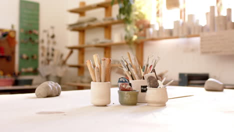 Brushes,-pottery-tools-and-clay-on-desk-in-pottery-studio