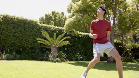 Focused-biracial-man-practicing-football-skills-in-sunny-garden,-copy-space,-slow-motion