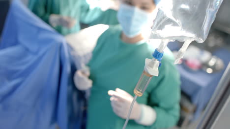 Kaukasische-Chirurgin-überprüft-Infusionsbeutel-Des-Patienten-Im-Operationssaal,-Zeitlupe