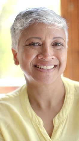 Vertical-video-of-portrait-of-happy-senior-biracial-woman-with-short-hair-at-home,-slow-motion