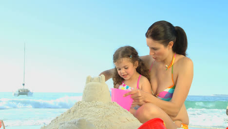 Attractive-mother-helping-her-daughter-to-build-a-sand-castle