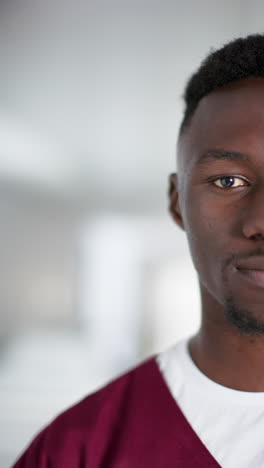 Vertical-video-of-portrait-of-happy-african-american-male-doctor-in-hospital,-slow-motion