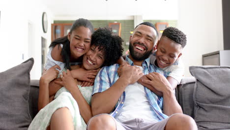 Retrato-De-Una-Feliz-Hija-E-Hijo-Afroamericanos-Abrazando-A-Sus-Padres-En-El-Sofá,-Cámara-Lenta