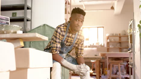 Happy-african-american-male-potter-resting-and-smiling-in-pottery-studio,-slow-motion