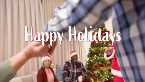 Animation-of-happy-holidays-text-over-diverse-senior-friends-dancing-at-christmas-at-home
