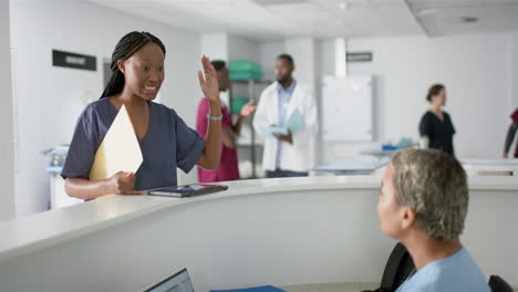 Diverse-female-doctors-discussing-work-at-reception-desk-at-hospital,-slow-motion