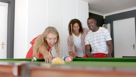 Young-Caucasian-woman-plays-pool-at-home,-flanked-by-friends