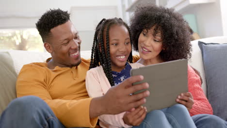 Happy-african-american-parents-with-daughter-using-tablet-at-home,-slow-motion