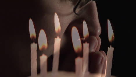 Animation-of-burning-candles-over-man-praying-on-black-background