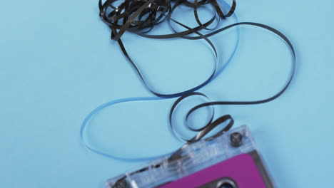 Video-of-retro-tape-with-pink-label-and-pulled-out-tape-with-copy-space-on-blue-background