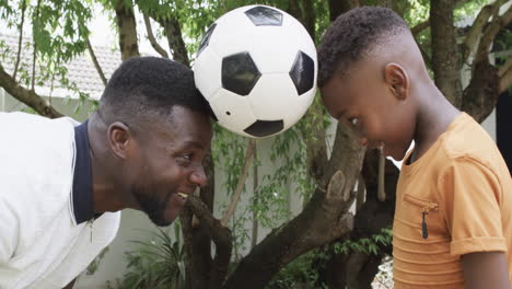 African-American-father-and-son-enjoy-a-playful-moment-outdoors-with-a-soccer-ball