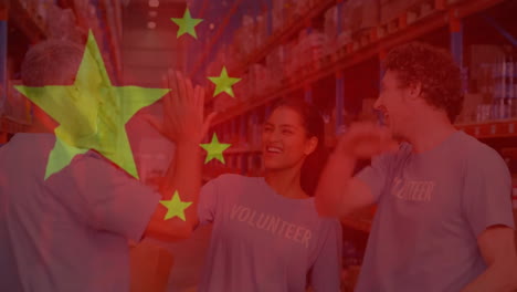 Animation-of-flag-of-china-over-diverse-male-and-female-volunteers-high-fiving-in-warehouse