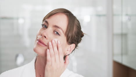 Middle-aged-Caucasian-woman-applies-facial-cream-at-home,-with-copy-space