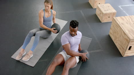 Fit-young-Caucasian-woman-and-African-American-man-exercising-at-the-gym-with-medicine-ball